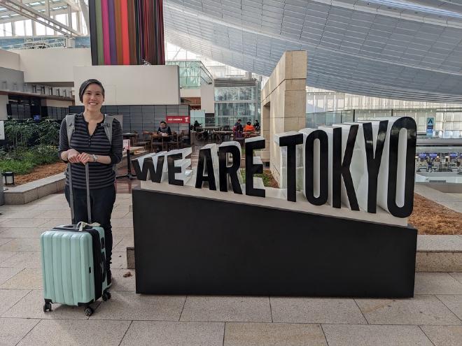 I stand next to a sign that reads &ldquo;We Are Tokyo&rdquo; inside Haneda Airport.