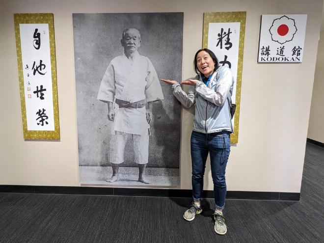 Van stands beside a life-sized photo of Kano Jigoro Shihan at the Kodokan