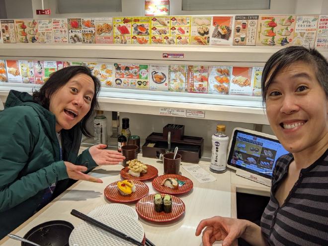 Van and I pose with our sushi dishes at a conveyor belt sushi restaurant.